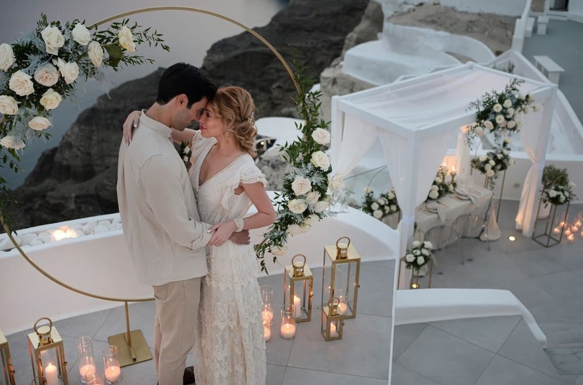 Intimate evening elopement with candles and floral arch in Santorini